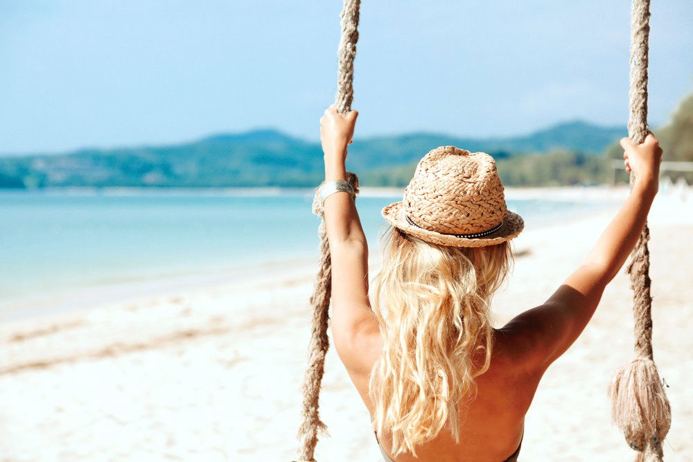 woman sitting on swing at the beach