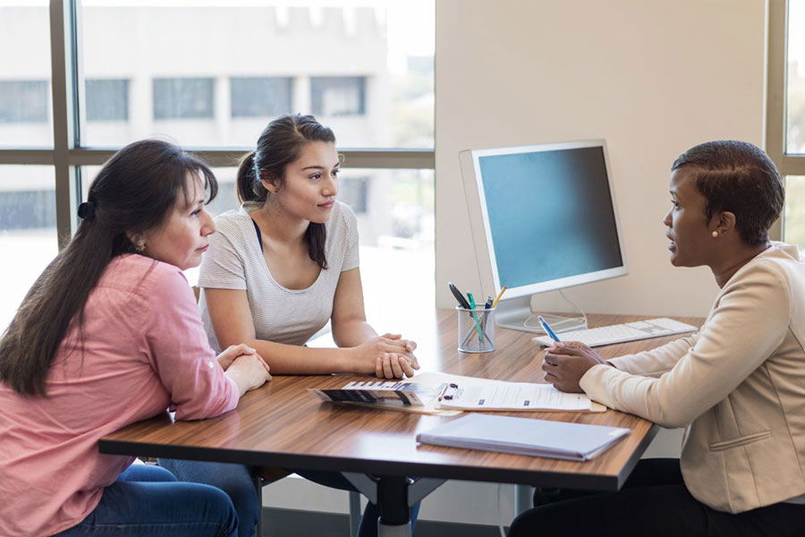 mother and daughter talking to loan officer