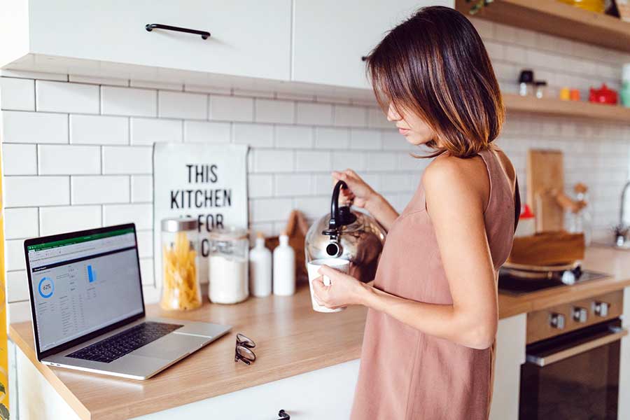 woman on laptop pouring coffee